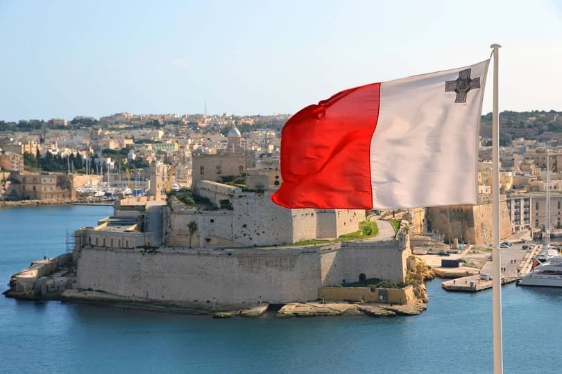 The National Flag of Malta flying prominently over Fort St. Angelo and the Valletta Grand Harbour