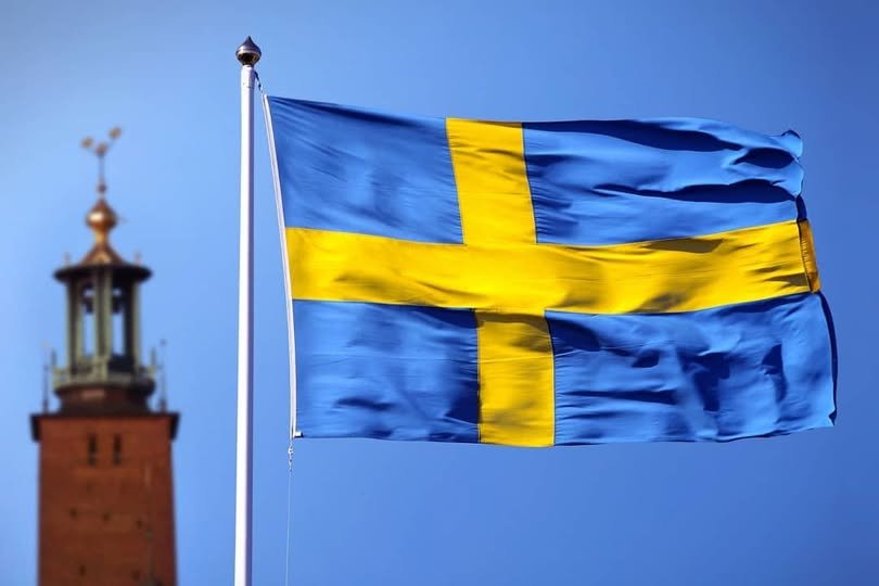 Swedish National Flag flying next to Stockholm City Hall tower